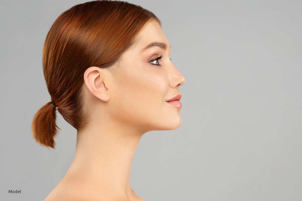 Woman in profile with auburn hair, gray studio background